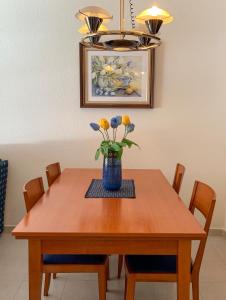 stół jadalny z wazonem kwiatów w obiekcie Apartamento Manhattan en el centro w mieście Escaldes-Engordany