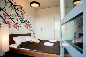 a bedroom with a bed with a tree mural on the wall at Platinum Towers E-Apartments in Warsaw