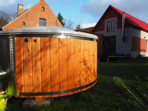 uma banheira de madeira sentada na relva ao lado de uma casa em Agroturystyka Gęsiniec Stare Osieczno em Stare Osieczno