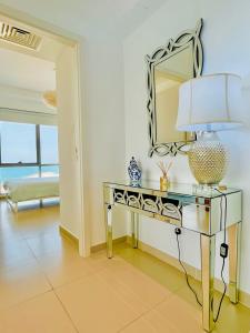 Cette chambre comprend une table avec une lampe et un miroir. dans l'établissement Luxurious 2 bedroom Beachfront Apartment - direct seaview, à Ras al Khaimah