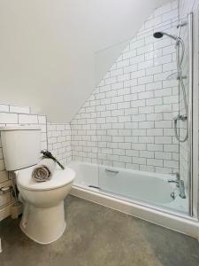 a bathroom with a toilet and a bath tub at Silverwood Coach House, with pre booked use of Indoor Swimming Pool in Frome