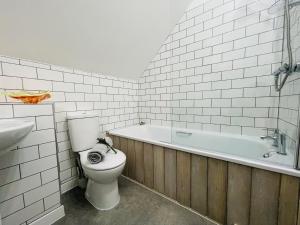 a bathroom with a toilet and a bath tub at Silverwood Coach House, with pre booked use of Indoor Swimming Pool in Frome +6 photos