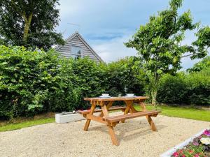 a wooden picnic table sitting in a garden at Silverwood Coach House, with pre booked use of Indoor Swimming Pool in Frome