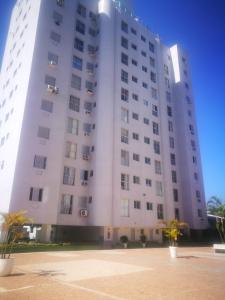 ein großes weißes Gebäude mit Palmen davor in der Unterkunft Apartamento com piscina 1 quarto de até 6 pessoas - Guarujá in Guarujá