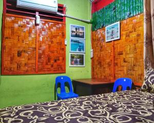 a bedroom with a bed and two blue chairs at Gonias Hostel in Gunungsitoli