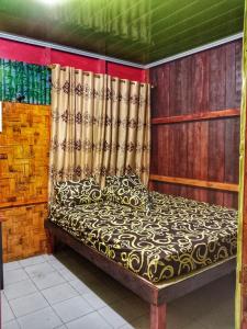 uma cama num quarto com cortinas em Gonias Hostel em Gunungsitoli