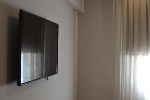 TV de pantalla plana colgada en la pared en Hotel Cervantes en Mendoza