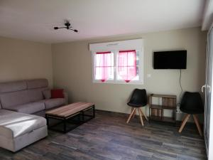 a living room with a couch and a flat screen tv at A l'ombre du ginkgo in Campagne-lès-Hesdin