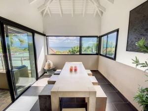 Großes Zimmer mit einem Tisch und einigen Fenstern in der Unterkunft Villa Zen, luxury and confort, private pool and sea view in Cul de Sac