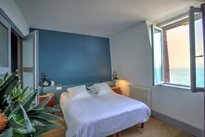 a bedroom with a bed and a large window at Hotel Le Rayon Vert in Étretat