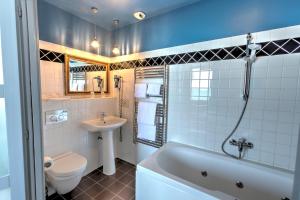 a bathroom with a tub and a toilet and a sink at Hotel Le Rayon Vert in Étretat