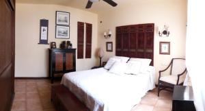 a bedroom with a white bed and a chair at Chalet Nº 7 Tajinaste in Puerto del Carmen