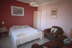 1 dormitorio con 1 cama blanca y 1 silla en Balcone Fiorito, en Menaggio