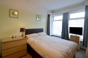 a bedroom with a bed and a dresser with a television at Brightwater family room for up to 3 people with shared facilities in Scarborough