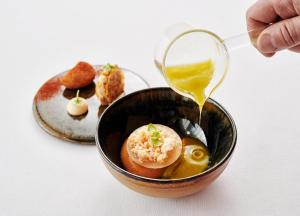 a person pouring mustard into a bowl of food at The Yeatman in Vila Nova de Gaia