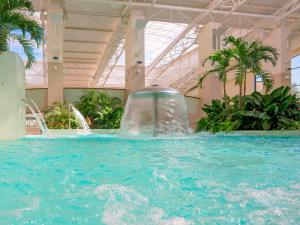 a large swimming pool with a fountain in a building at Lotus Therm Spa&Luxury Resort in Baile Felix