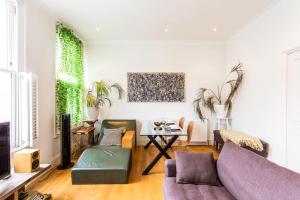 倫敦的住宿－Bright and Spacious Notting Hill Nest，客厅配有紫色沙发和桌子