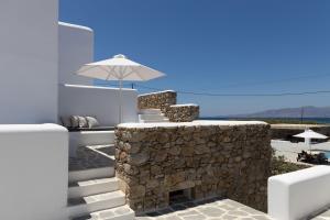 a building with a stone wall and an umbrella at Archon Seaside Retreat in Plaka