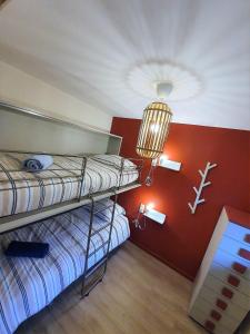 2 Etagenbetten in einem Zimmer mit einer roten Wand in der Unterkunft Chamonix Appartement Vue Mont Blanc avec Jardin in Chamonix-Mont-Blanc