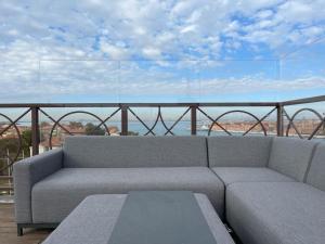 un sofá en un balcón con vistas al océano en The Venice Penthouse and Rooftop-Terrace at Molino Stucky en Venecia