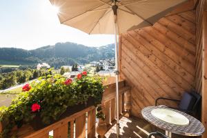 a balcony with an umbrella and a table and flowers at Hotel Garni Hubertushof in Fiss