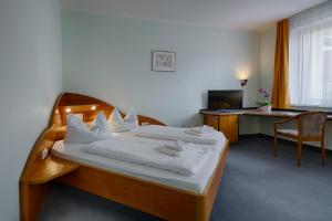 a bedroom with a bed with white sheets and a desk at Hotel Sophienhof in Königs Wusterhausen