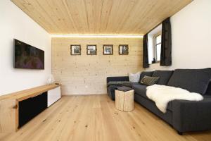 een woonkamer met een grijze bank en een houten plafond bij Chalet 14 in Sankt Gallenkirch