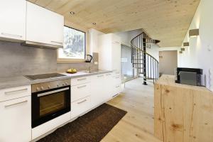 een keuken met witte kasten, een wastafel en een fornuis bij Chalet 14 in Sankt Gallenkirch