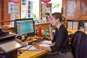 Una donna che parla al telefono a una scrivania con un computer di Camping de la Liez a Peigny