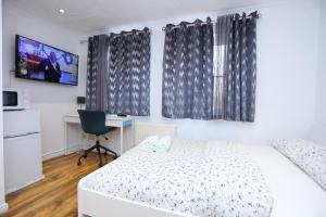 een slaapkamer met een bed, een bureau en een televisie bij Fabulous Room with en-suite bathroom and shared kitchen in Thamesmead