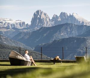 a woman and a dog sitting in a boat in the mountains at Granpanorama Wellnesshotel Sambergerhof Superior in Villandro