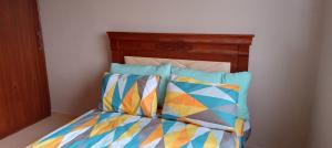 a bed with a wooden headboard and two colorful pillows at Appartement près de casanearshore et l'OFPPT in Casablanca