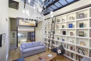 Loft center of Paris by Studio prestige في باريس: غرفة معيشة مع أريكة زرقاء ورف كتاب