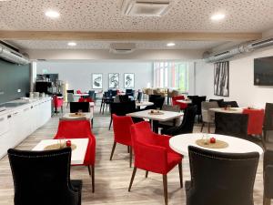 a dining room with tables and red chairs at DORMERO Hotel Deggendorf in Deggendorf