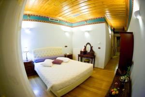 a bedroom with a white bed and a wooden ceiling at Kyveli Suites in Nafplio