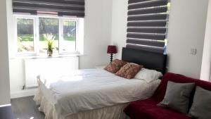 una camera con un letto bianco e un divano rosso di Quiet Studio by Lloyd Park a South Norwood