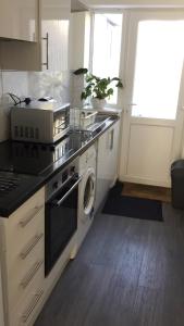 a kitchen with a stove and a washer and dryer at Quiet Studio by Lloyd Park in South Norwood