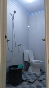 a bathroom with a shower and a toilet and a tub at Kalandra Guest House in Ponorogo