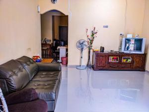 a living room with a leather couch and a tv at Homestay Kak soh at KampungKalai, Jeli Kelantan in Jeli