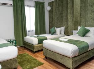 two beds in a room with green curtains at Hotel Majestic in Casablanca