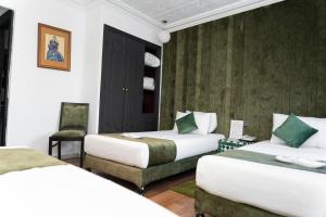 a hotel room with two beds and a chair at Hotel Majestic in Casablanca