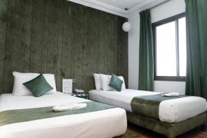 two beds in a room with green curtains at Hotel Majestic in Casablanca