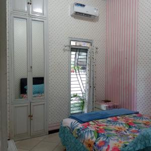 a bedroom with a bed and a cabinet and a window at Kalandra Guest House in Ponorogo