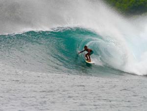 Un uomo che cavalca un'onda su una tavola da surf nell'oceano di Barrel Homestay Areguling a Kuta Lombok
