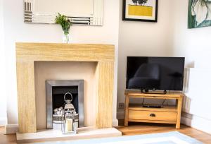 sala de estar con chimenea y TV en Kerns Cottage Stratford-upon-Avon en Stratford-upon-Avon