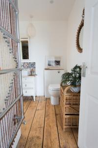 a bathroom with a toilet and a wooden floor at Fairlight - Charming coastal home on the beach in Chichester +32 photos