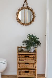 a mirror on top of a wicker cabinet in a bathroom at Fairlight - Charming coastal home on the beach in Chichester