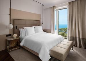 una camera da letto con un grande letto bianco e una grande finestra di San Domenico Palace, Taormina, A Four Seasons Hotel a Taormina