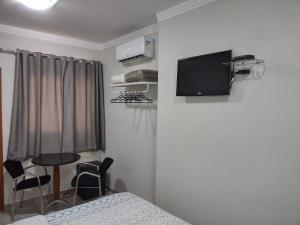 Ipê Suítes في دومينغوس مارتينز: غرفة نوم بسرير وتلفزيون على جدار
