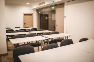 uma sala de aula vazia com mesas e cadeiras brancas em Oca Oriental Porto Hotel no Porto